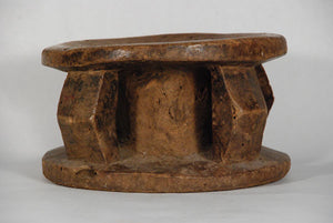 African lega stool with four sculpted columns supporting the base and the worn